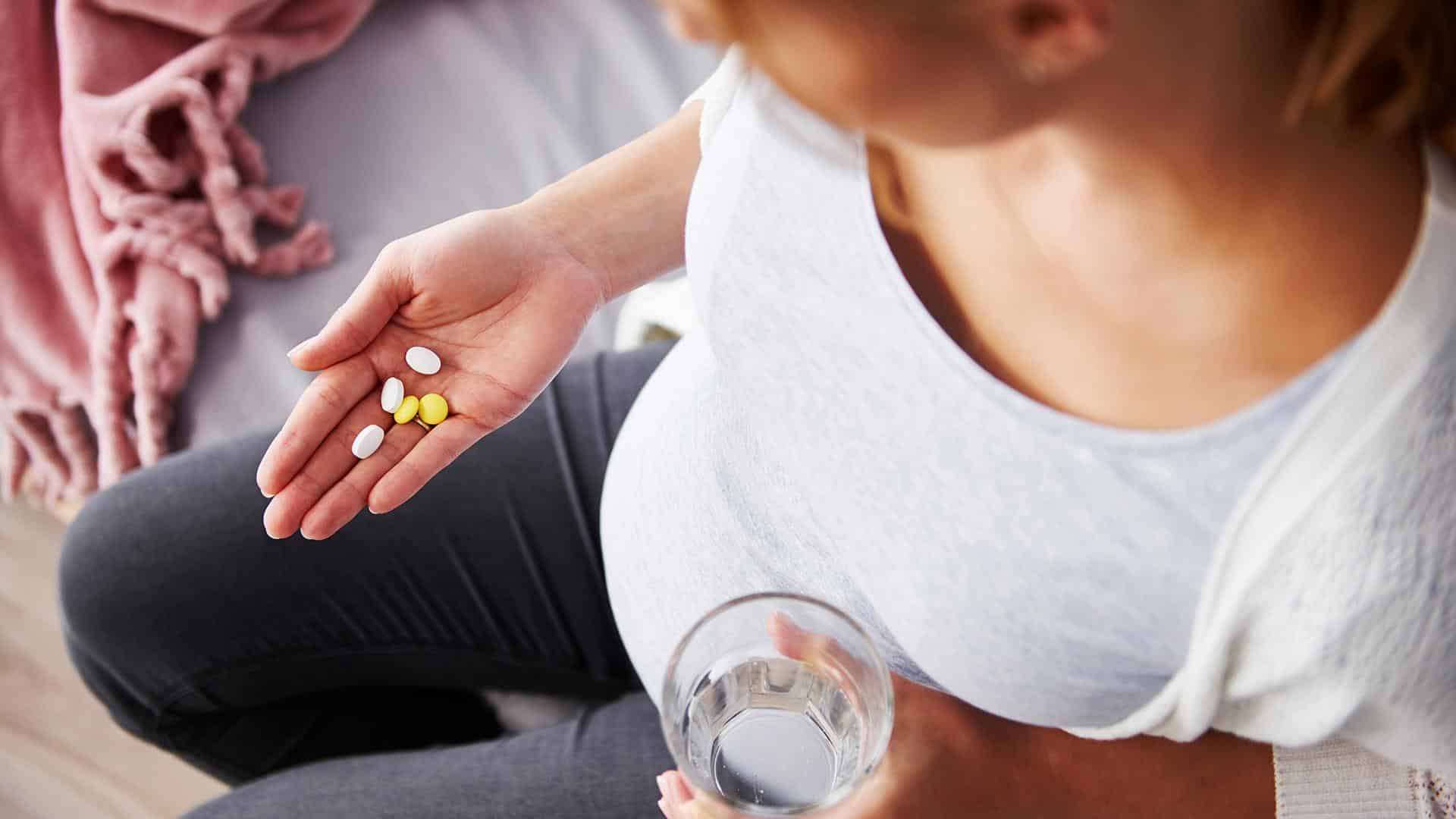 Mulher grávida com suplementos na mão