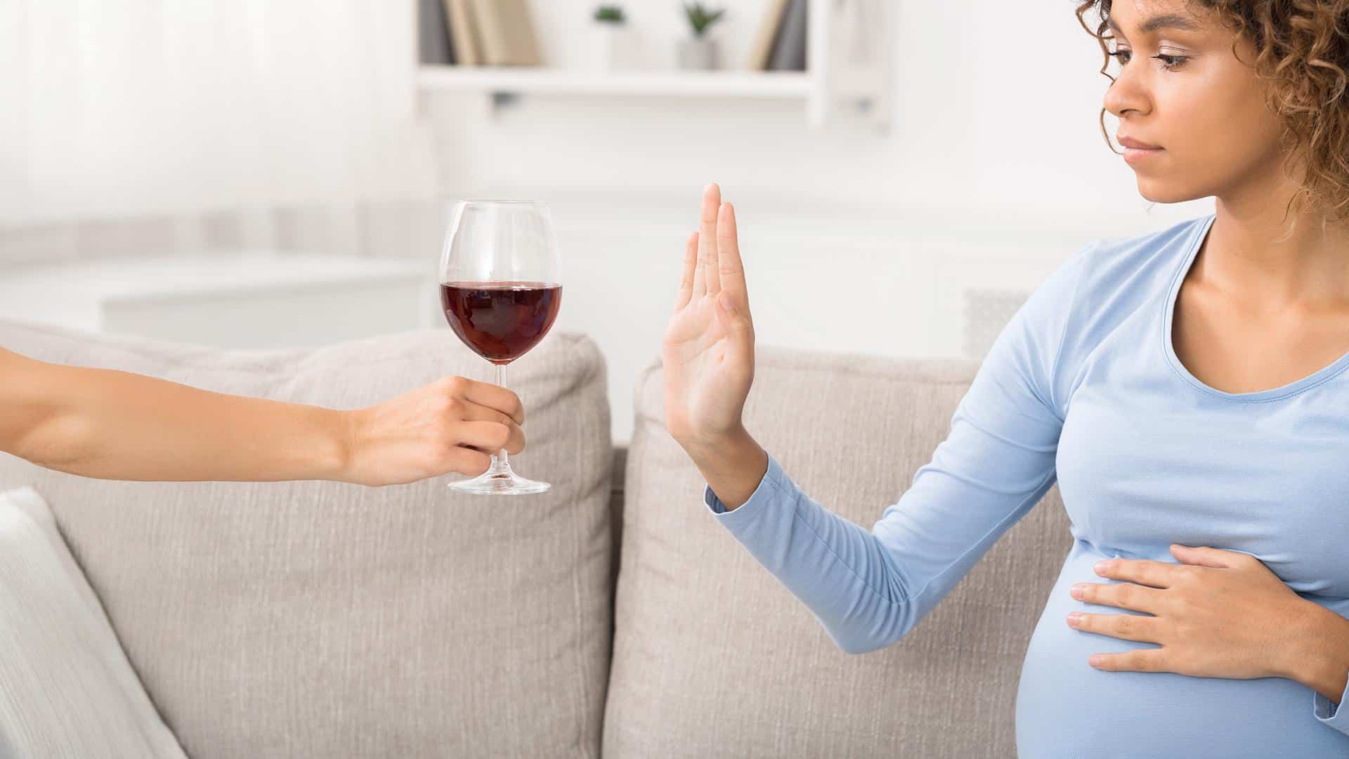 Gestante negando uma taça de bebida alcoólica