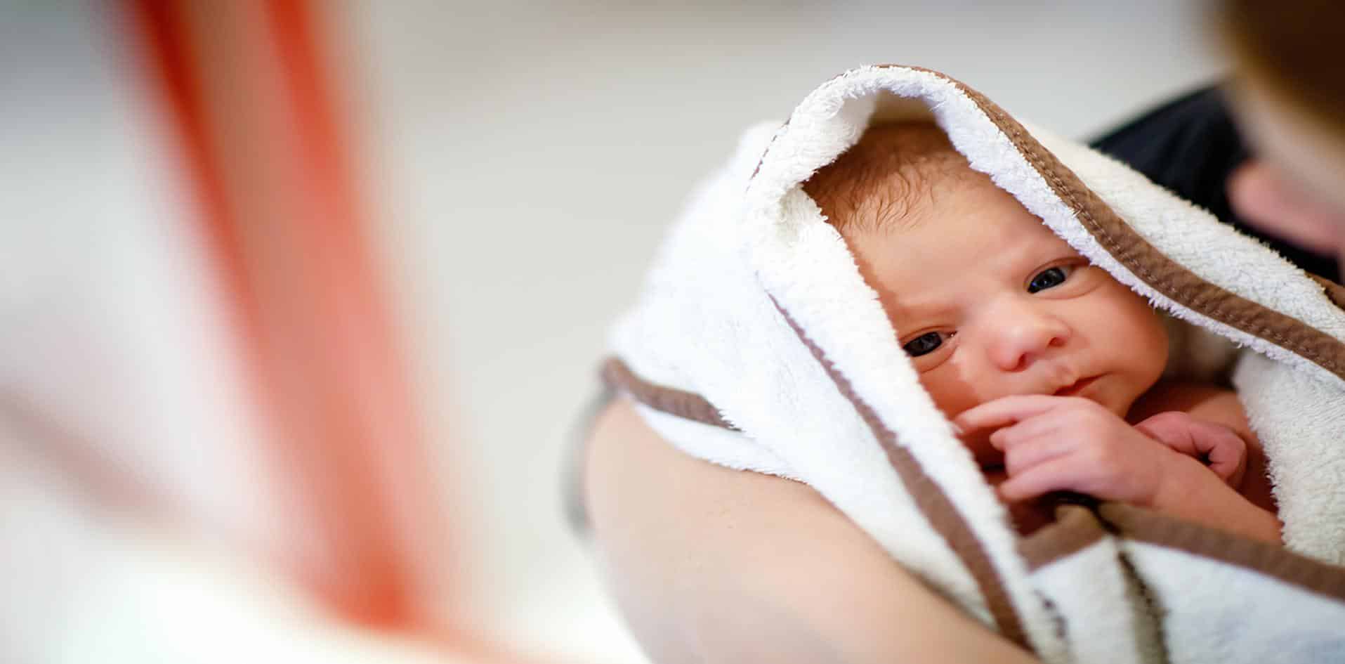 Bebê enrolado em toalha