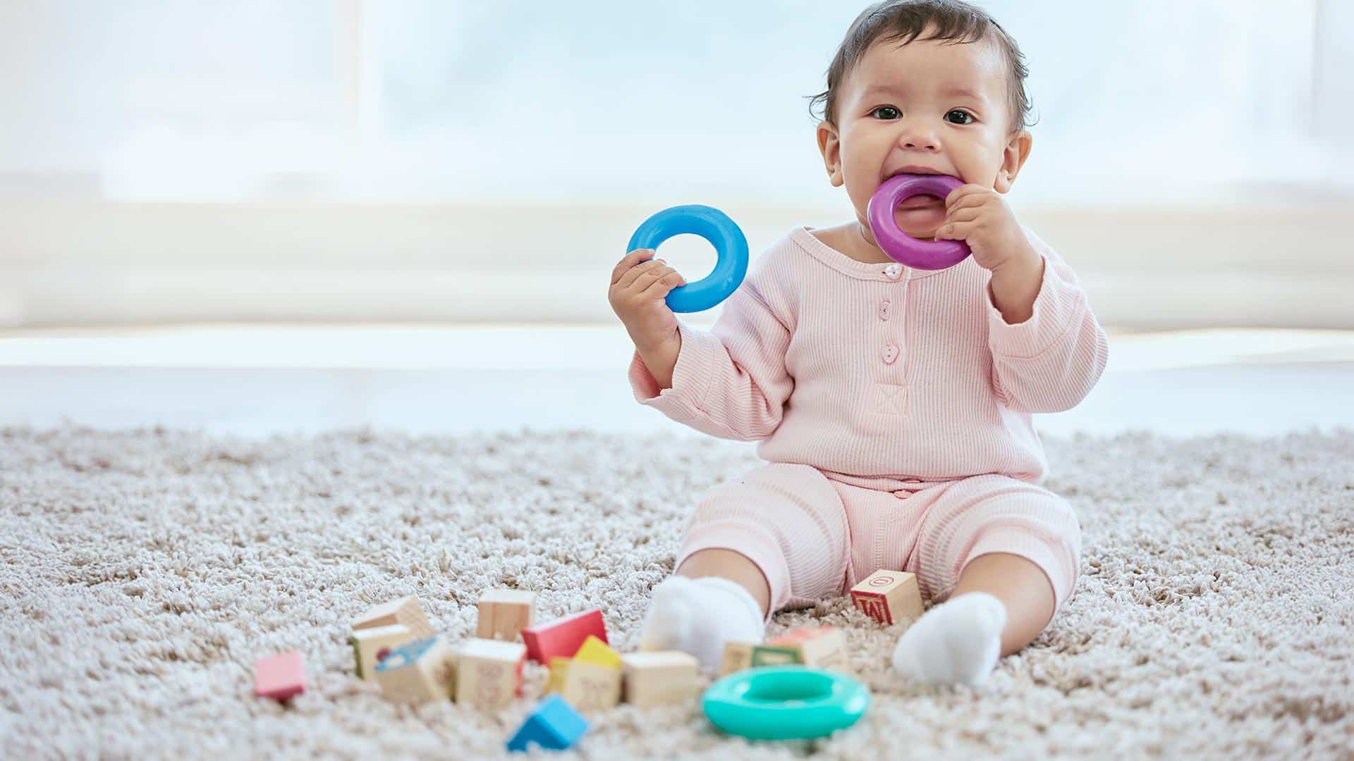 Bebê colocando objetos de brinquedo na boca